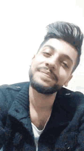 a man with a beard is taking a selfie and smiling for the camera .