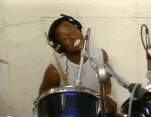 a man wearing headphones is playing drums and making a funny face