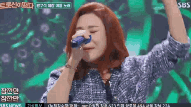 a woman singing into a microphone with sbs news written on the bottom