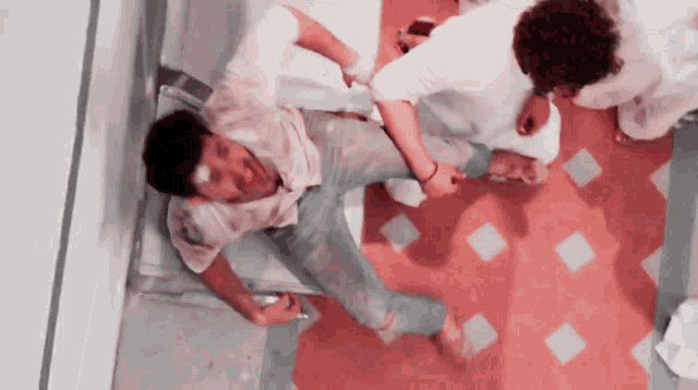 a man with a bandage on his head is laying on a red tiled floor