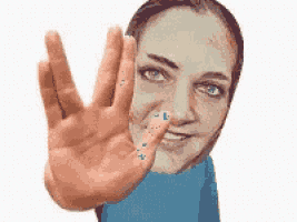 a woman in a blue shirt making a stop sign with her hand
