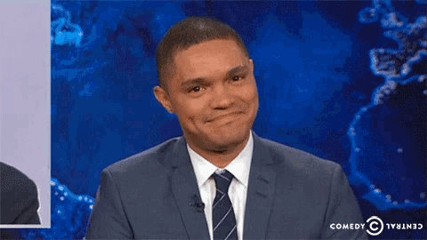 a man in a suit and tie is smiling in front of a comedy central logo .