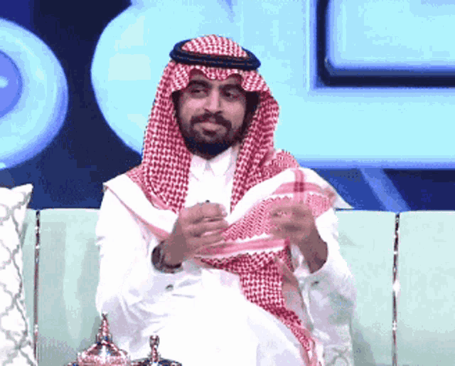 a man in a traditional arabic costume sits on a green couch