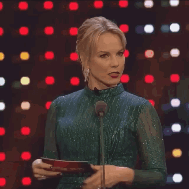 a woman in a green dress is holding a red card