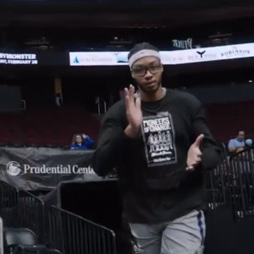a man in a black shirt stands in front of a prudential center banner