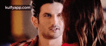 a man and a woman are looking at each other . the man is wearing a red shirt .