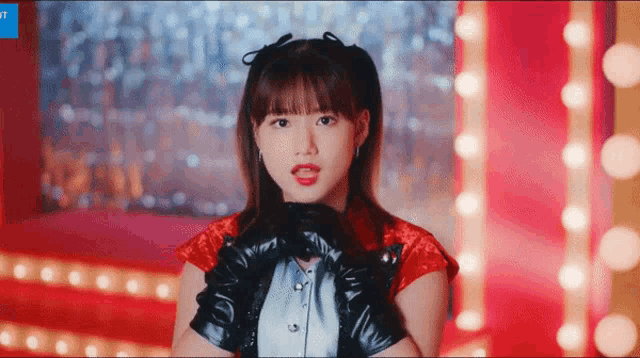 a girl wearing a red top and black gloves is looking at the camera