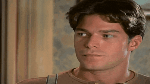 a man with a serious look on his face is wearing a brown shirt .