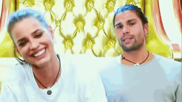 a man and a woman are sitting on a couch and smiling .