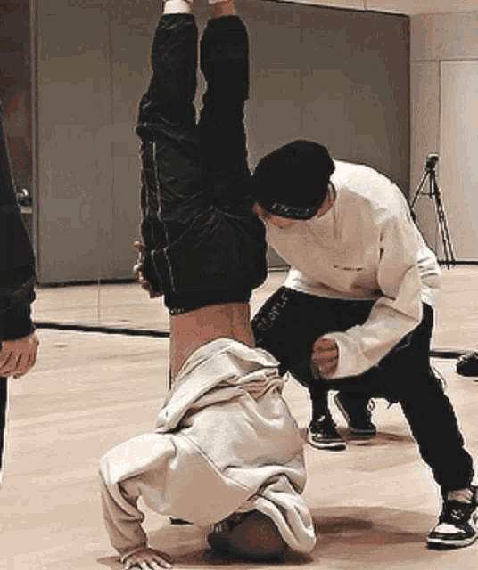 a man is doing a handstand while another man helps him up