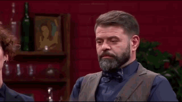 a man with a beard and bow tie is sitting in front of a woman .