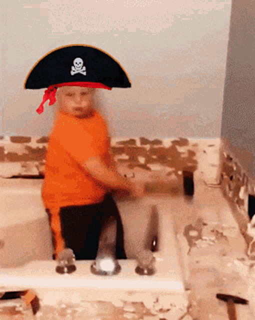 a young boy wearing a pirate hat is sitting in a bath tub