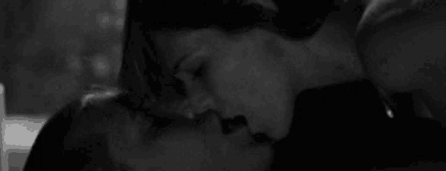 a black and white photo of a man and woman kissing each other .