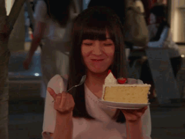 a woman is eating a piece of cake with whipped cream and a strawberry on top