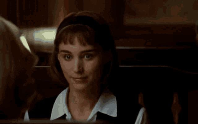 a woman is sitting in a dark room and smiling at the camera .