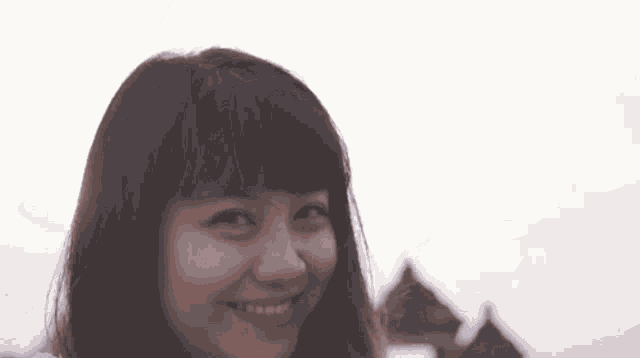 a close up of a woman 's face smiling with a building in the background .