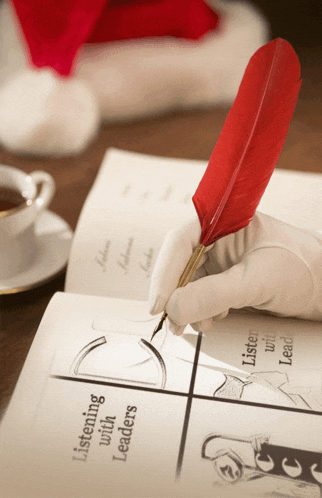 a person is writing with a red feather in a book that says listening with leaders