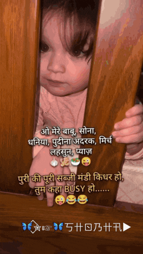 a baby peeking out from behind a wooden railing with a caption in a foreign language