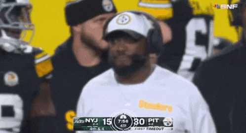 a man wearing headphones stands in front of a scoreboard during a football game between the steelers and the jets