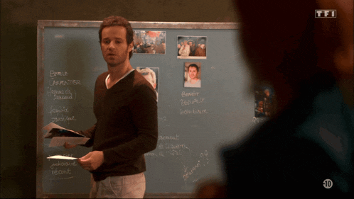a man stands in front of a chalkboard that says tfi on it