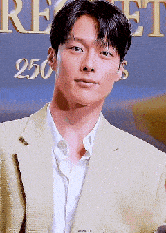 a young man in a suit and white shirt is standing in front of a sign that says 250 .