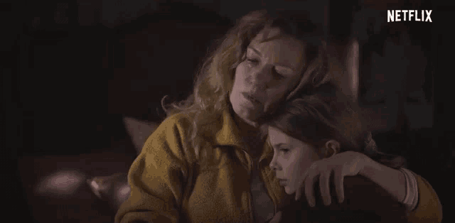 a woman is hugging a little girl in a dark room .
