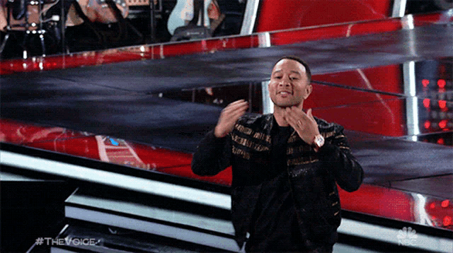 a man on a stage with #thevoice written on the bottom right