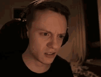 a young man wearing headphones is making a funny face .