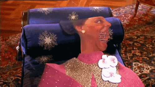 a woman in a pink dress is laying on a chair