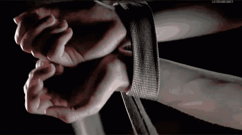 a close up of a person 's hands tied up with a bracelet with the words later on grey visible