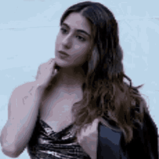 a woman in a strapless dress is holding a black jacket over her shoulder and looking at the camera .