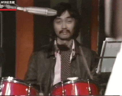 a man is playing drums in front of a microphone with jp written on the bottom right