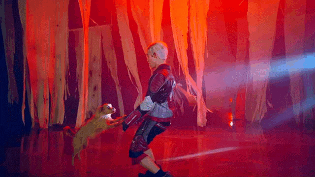 a man is holding a small dog in his arms in front of a red background