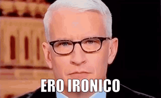a man wearing glasses and a suit is making a funny face and saying ero ironico .