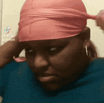 a woman is wearing a pink headband on her head and making a funny face .