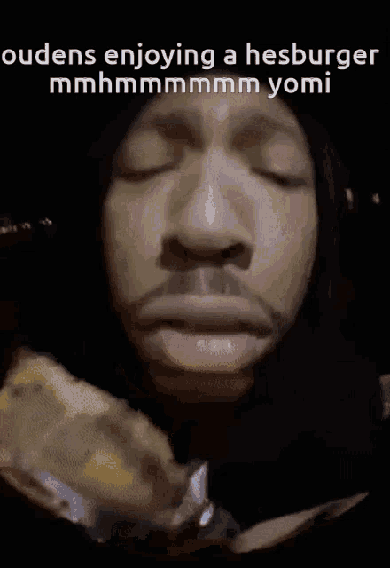 a close up of a person eating a hamburger with the caption " oudens enjoying a hesburger mmhmmmmmm yomi "