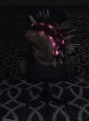 a person is sitting in a chair in a dark room with a helmet on their head .