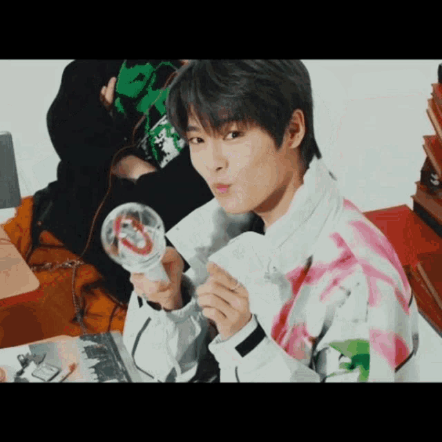 a young man is holding a light stick in his hand and making a face .
