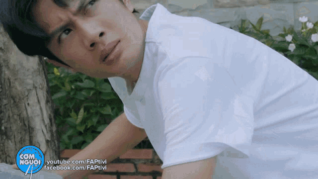 a man in a white shirt is looking up with a facebook.com logo in the background