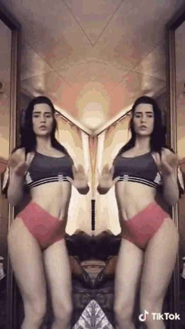 a woman is dancing in front of a mirror with tik tok written on the bottom