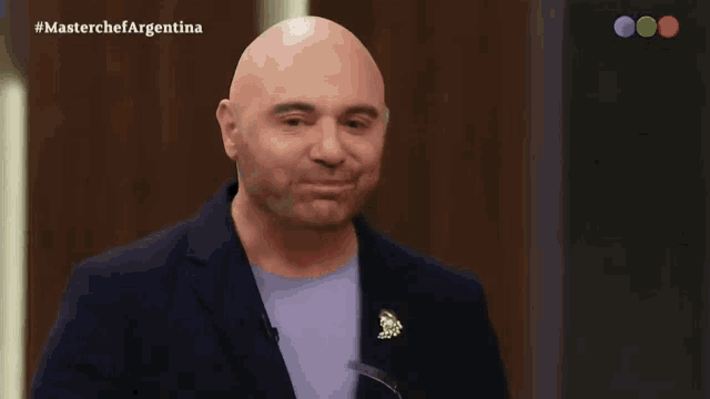 a bald man says " ta bueno " in front of a masterchef argentina logo