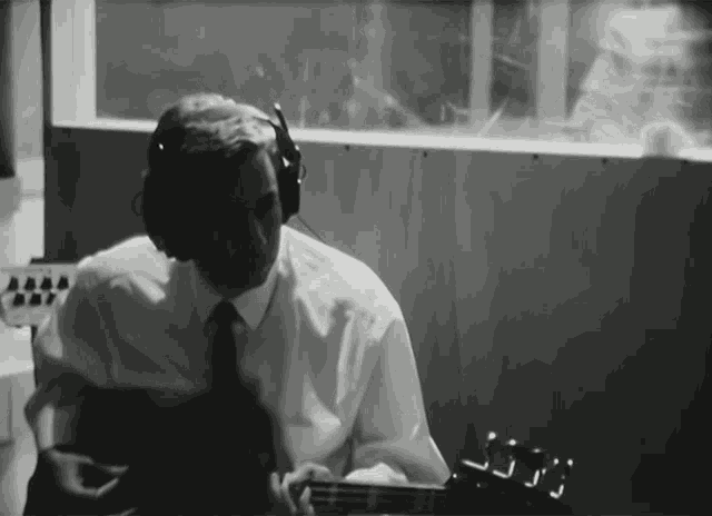 a man wearing headphones playing a guitar in a dark room