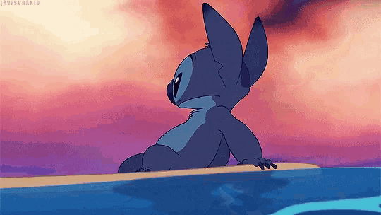 stitch is sitting on the edge of a body of water .