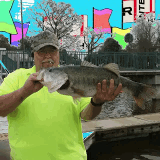 a man in a yellow shirt holds a large fish in his hands