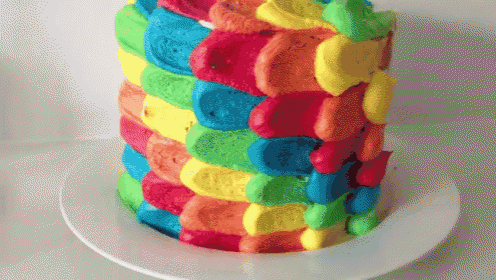 a white plate with a rainbow colored cake on it