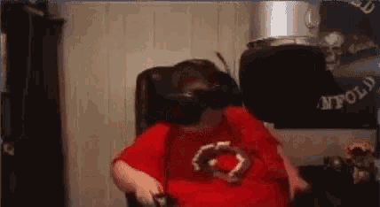 a man wearing a virtual reality headset is sitting in a chair in a room .