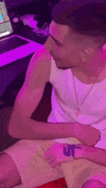 a man in a white tank top has a tattoo on his wrist .