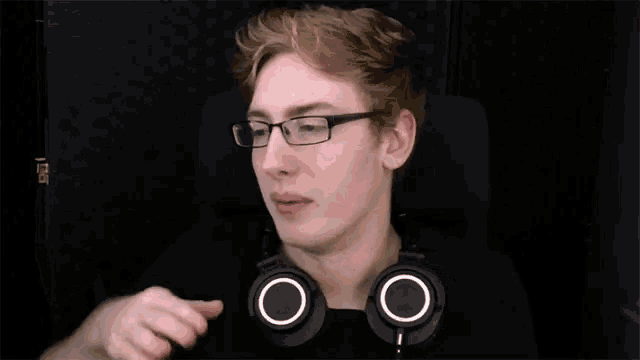a man wearing glasses and headphones is sitting in a chair .