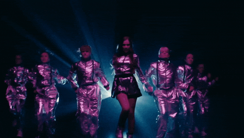 a group of women in shiny metallic outfits are dancing