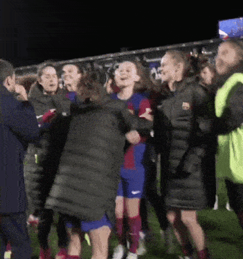 a group of people on a soccer field with one wearing a jacket that says fc barcelona